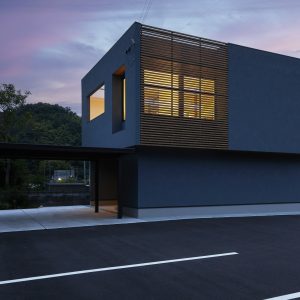 木の格子と塗り壁の外壁が合わさった夜景の外観。