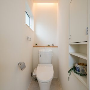 正面の壁に間接照明と、２段のニッチを設けたシンプルなトイレ空間