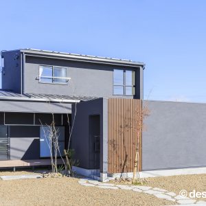 ブルーグレーの塗り壁が特徴の住まいの昼の外観