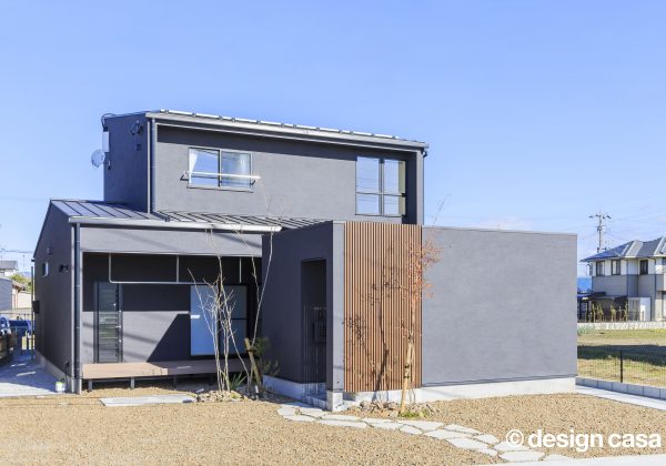 ブルーグレーの塗り壁が特徴の住まいの昼の外観