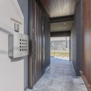 ダークブラウンの玄関ドアと屋根・格子付きの玄関ポーチ