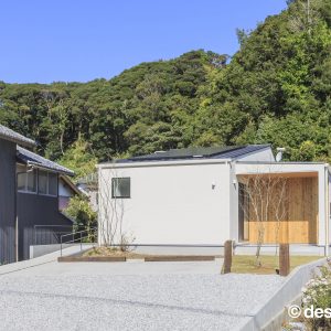 アクセントの木目が映える白い住まいの昼の外観