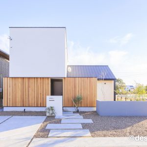 白と木目の外壁に、ネイビーの屋根がアクセントの住まいの外観