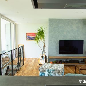 テレビ裏のグレーのアクセントクロスと大きな植栽のあるリビング