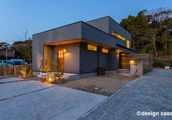 質感にこだわった塗り壁と木目の玄関ドアの夜景外観