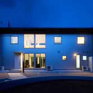 吹きぬけリビングの窓からあかりがこもれる夜の外観