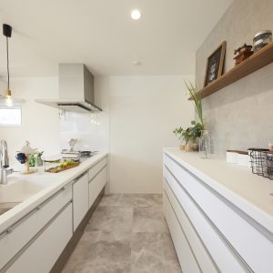 薄いグレーのフロアタイルを採用した白いキッチン