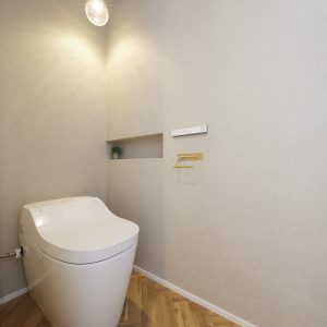 ペンダントライトの灯りがほんのりと灯る、グレーを基調としたシンプルなトイレ空間。