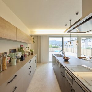 グレーのキッチンとカップボード、木の吊り戸棚の組み合わせがやわらかい雰囲気を出すキッチン。